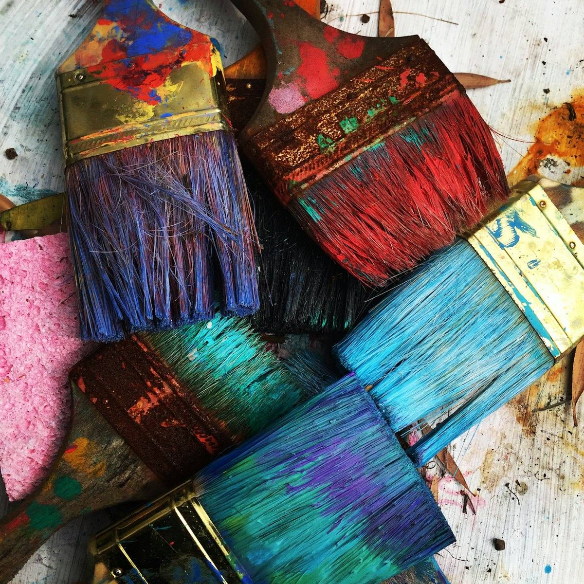 Paint brushes with bright colours on a painted surface
