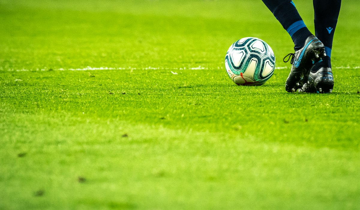 A player dribbling a football on a grass pitch